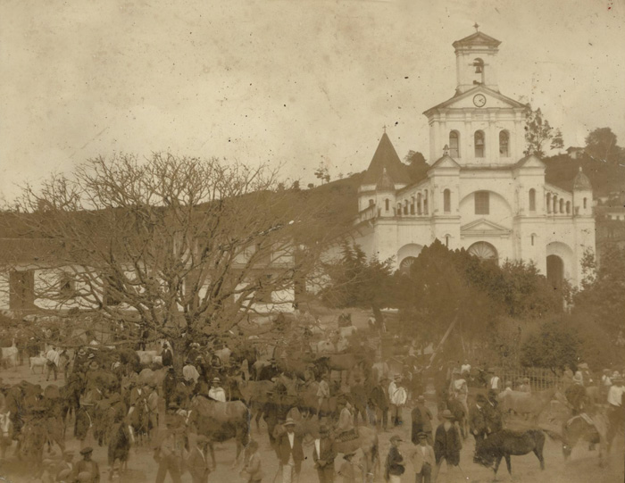 Feria en el Parque Principal, al fondo la Iglesia de Nuestra Señora de la Asunción (década de 1930). Cortesía Secretaría de Cultura y Turismo de Marinilla.